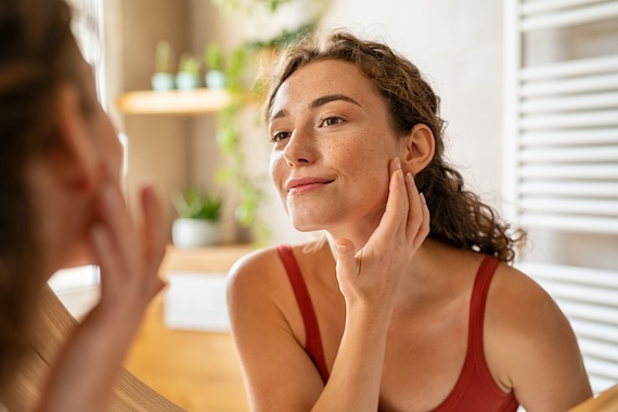 Clariant Image Beauty girl looking at mirror while touching her face 20230605